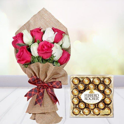 Bouquet of pink and white roses wrapped in burlap with a red ribbon, next to a box of Ferrero Rocher chocolates on a light background.
