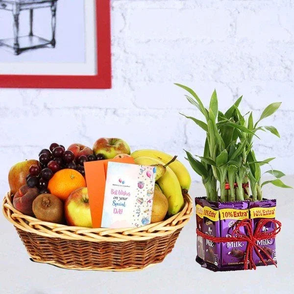 Fruit basket with a card and a set of packets next to a green plant on a white surface.