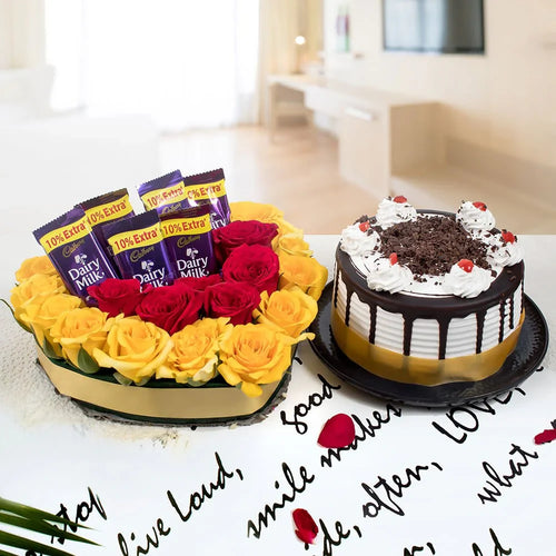 Bouquet of yellow and red roses with Cadbury Dairy Milk chocolate bars and a chocolate cake on a table.