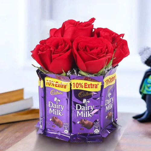 Red roses in a container made of Cadbury Dairy Milk chocolate bars on a light background