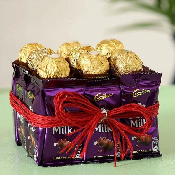 Cadbury chocolate bars arranged in a pyramid shape with a red ribbon on a light green surface.