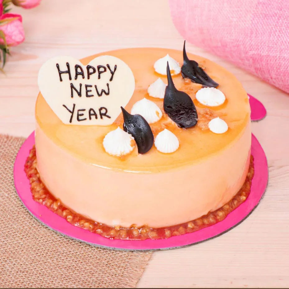 Round cake with 'Happy New Year' decoration on a pink plate