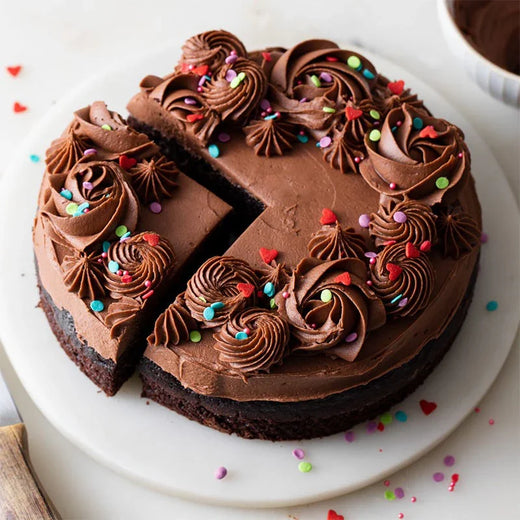 Half kg chocolate cake with chocolate frosting and colorful sprinkles on a white plate