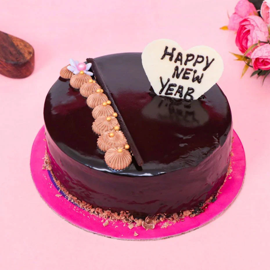 Chocolate cake with 'Happy New Year' decoration on a pink background