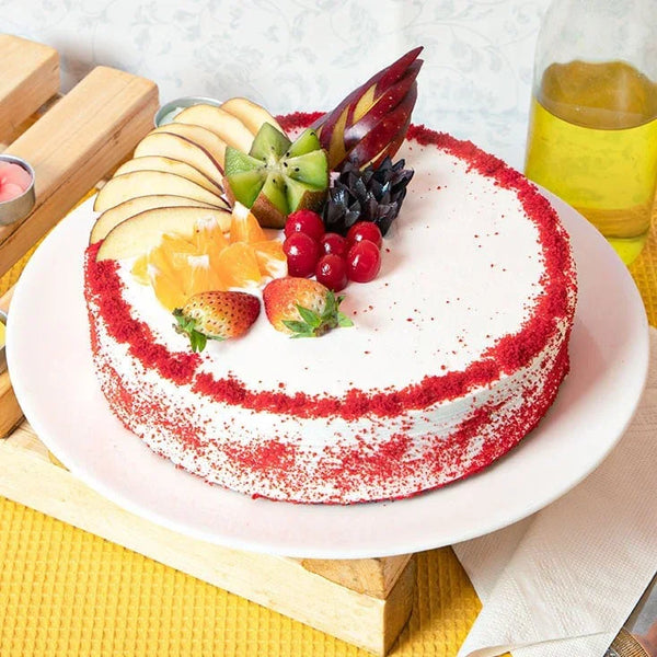 Red velvet fruit cake topped with fresh fruits on a white plate