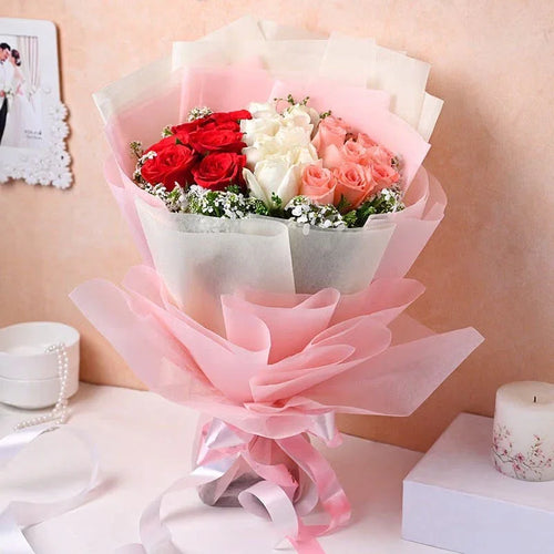 Bouquet of red, white, and pink roses wrapped in pink paper on a light background