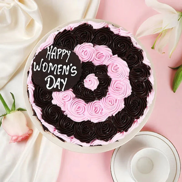 Decorative cake with pink and black icing on a pink background with flowers