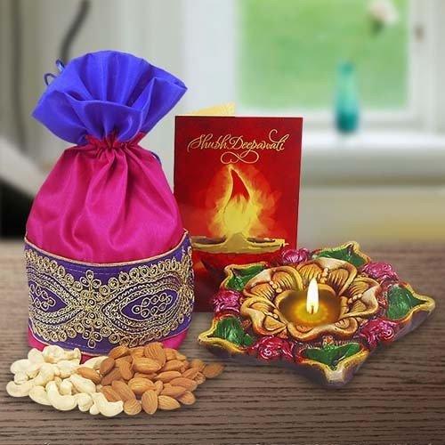 Festive gift set with embroidered pouch of dry fruits, decorative diya, and greeting card on table