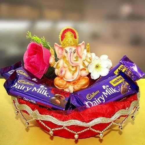 Ganesh idol with Dairy Milk chocolates, rose, and flowers in decorative tray, gift arrangement