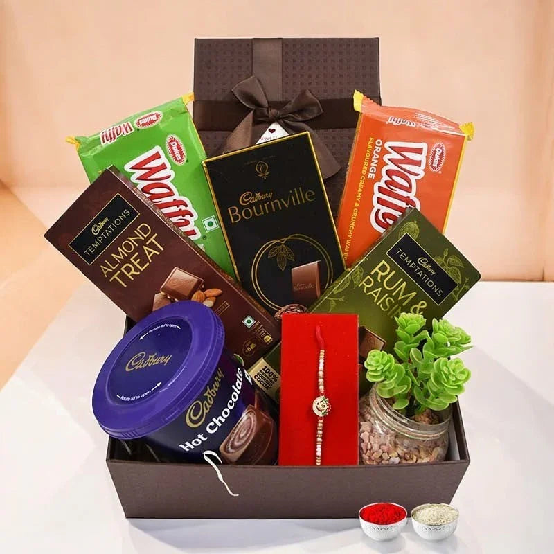 Gift basket with Cadbury products, a plant, and other items on a white surface.