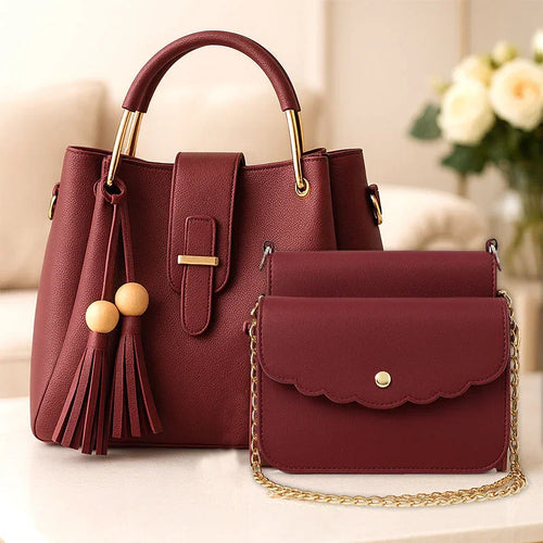 Maroon handbag with gold accents and matching pouch on a light surface.