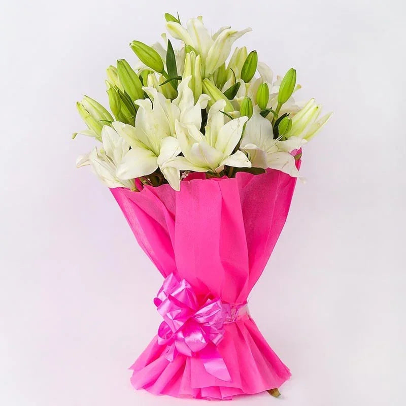 Bouquet of white and green flowers wrapped in pink paper with a bow on a light gray background