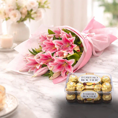Bouquet of pink flowers and box of Ferrero Rocher chocolates on a marble surface.