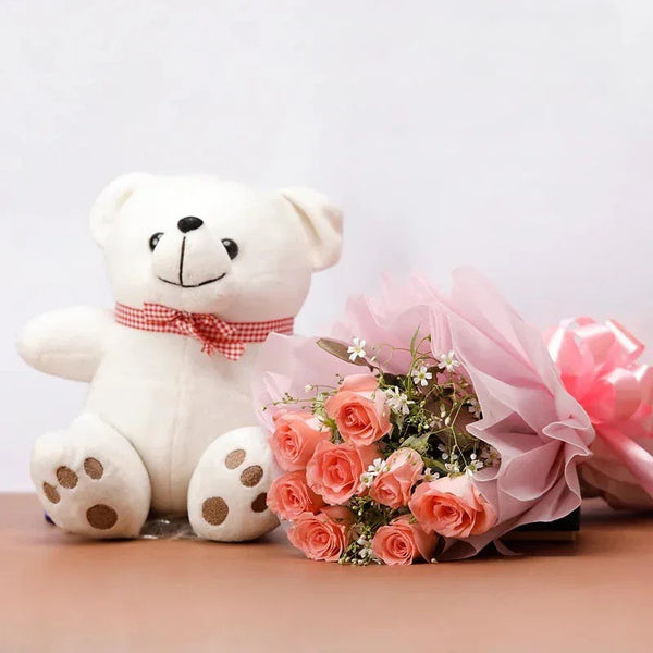 White teddy bear with a pink bow next to a bouquet of pink roses on a light background