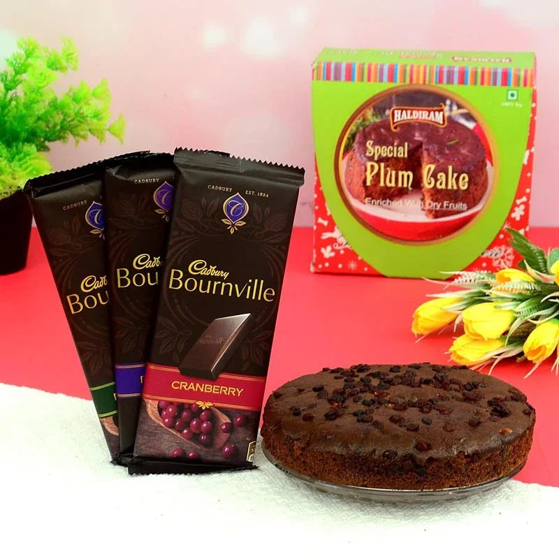 Cadbury Bournville chocolate bars and a plum cake on a pink surface with flowers.