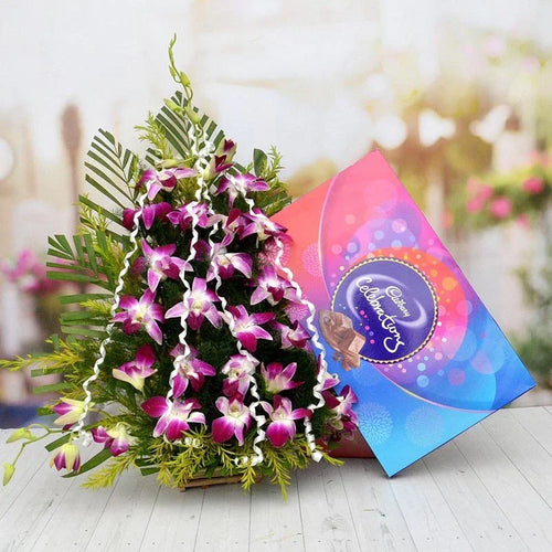 Bouquet of purple orchids with a Cadbury chocolate box on a blurred background