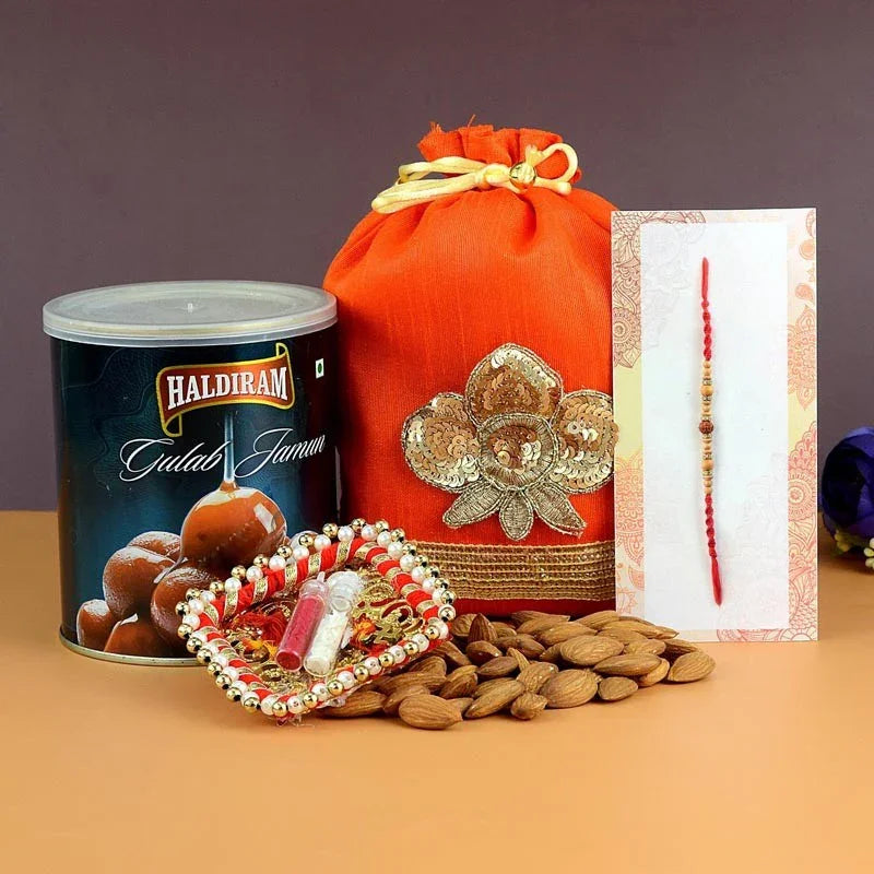 Gulab Jamun can, red bag with gold embroidery, almonds, and a Rakhi card on a brown background