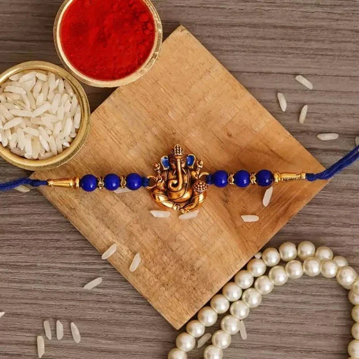 Decorative bracelet with blue and gold beads on a wooden surface with rice and a pearl necklace.