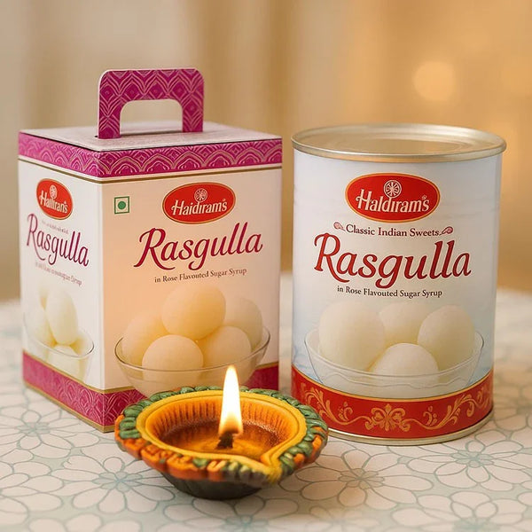 Rasgulla sweets gift box and tin with lit Diwali diya on festive table