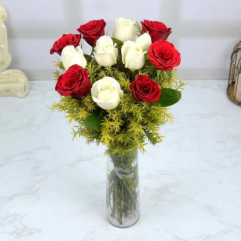 Bouquet of red and white roses in a clear vase on a marble surface.
