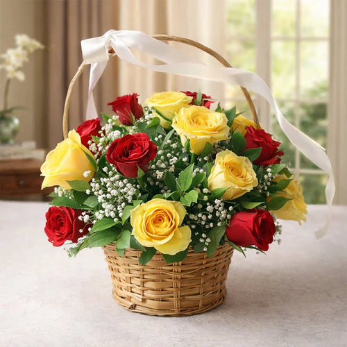 Basket of red and yellow roses with a white ribbon on a light surface.