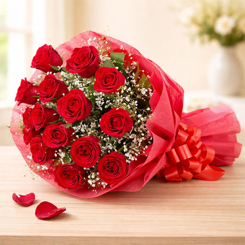 Bouquet of red roses with a pink ribbon on a wooden surface