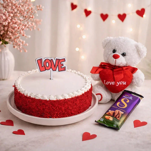Red velvet cake with 'LOVE' topper, white teddy bear with 'Love you' message, and Cadbury Dairy Milk chocolate bar on a decorative background.