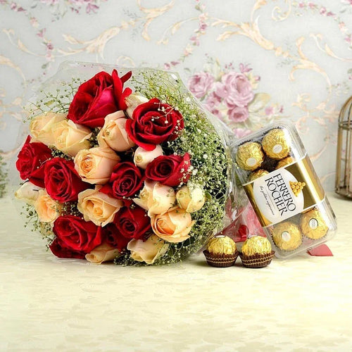 Bouquet of red and beige roses with a box of Ferrero Rocher chocolates on a decorative background.