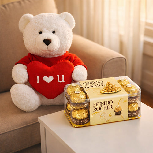 White teddy bear with a red heart and 'I ❤️ U' text next to a box of Ferrero Rocher chocolates on a couch.