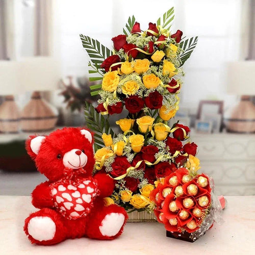 Red teddy bear and floral arrangement with chocolate bouquet on a table.