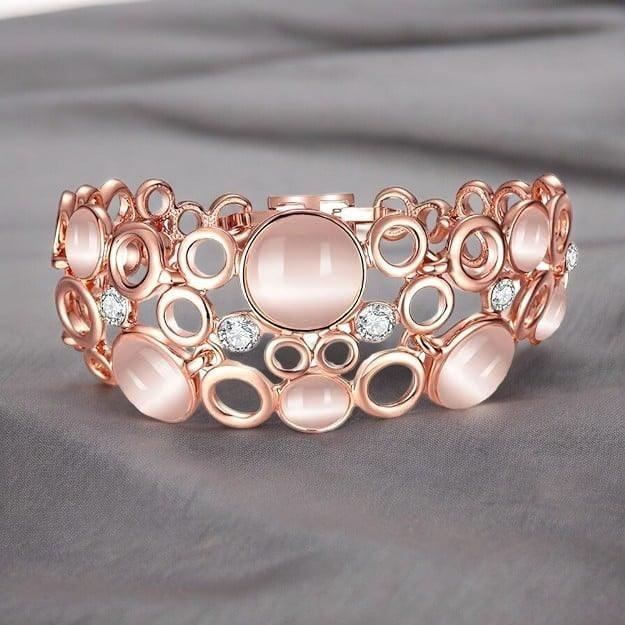 Rose gold bracelet with pink stones and diamonds on a gray background