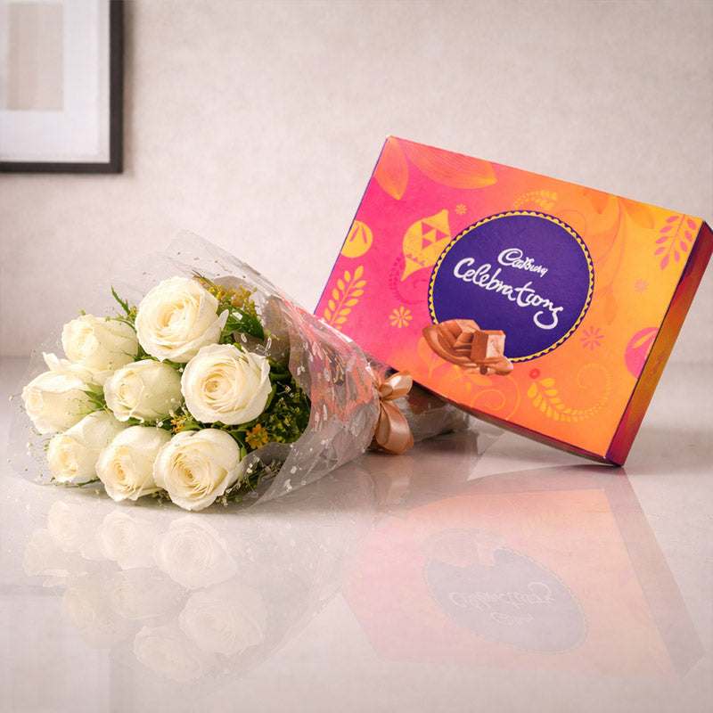 Bouquet of white roses and Cadbury Celebrations chocolate box on a light surface.
