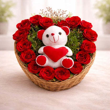 Heart-shaped basket with red roses and a plush teddy bear holding a red heart