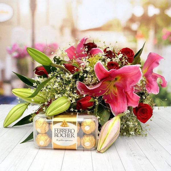 Bouquet of flowers with a box of Ferrero Rocher chocolates on a wooden surface.