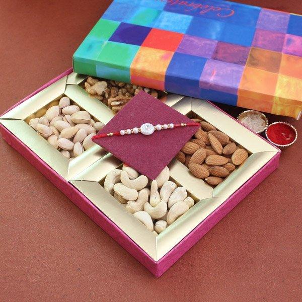 Gift box with assorted dry fruits, a decorative rakhi, and festive kumkum containers