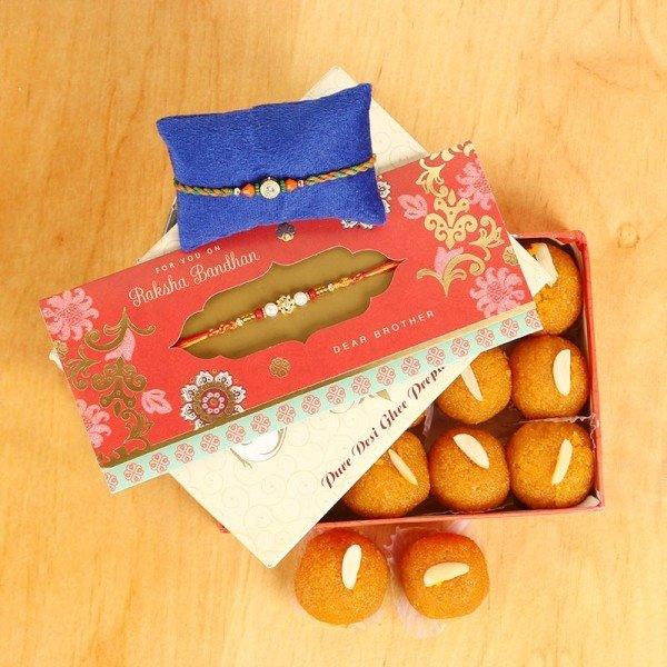 Rakhi with decorative box and Indian sweets arranged on a wooden surface