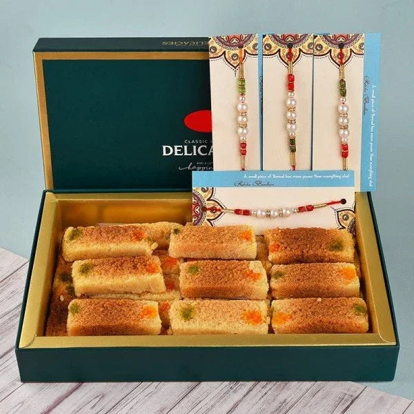 Box of assorted Indian sweets with four decorated Rakhi bracelets on display