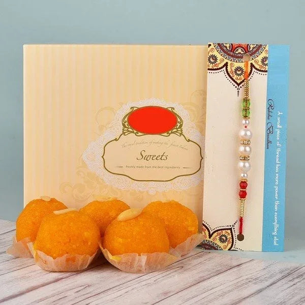 Traditional rakhi with pearl beads and box of Indian sweets ladoo for Raksha Bandhan gifting