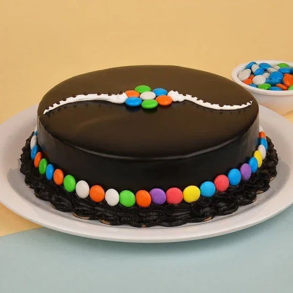 Chocolate cake with glossy icing decorated with colorful candy and white cream on a plate