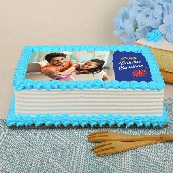 Rectangular Raksha Bandhan cake with blue icing and photo of brother and sister, festive decor