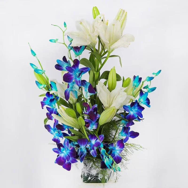 Bouquet of blue and white flowers in a clear vase on a white background
