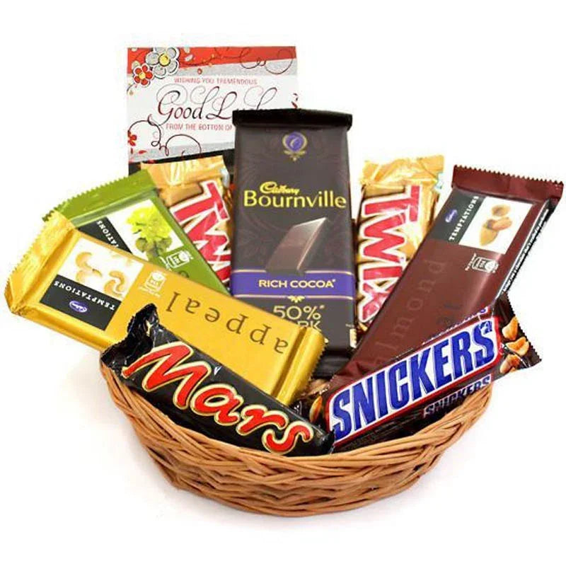 Basket of assorted chocolate bars including Mars, Snickers, Twix, and Bournville on a white background.