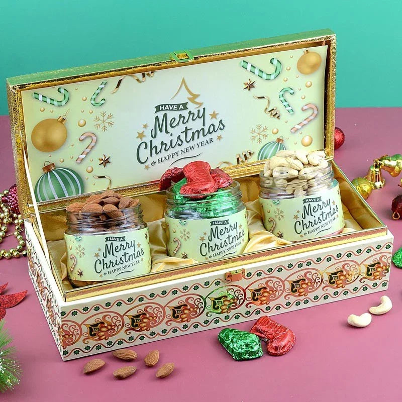 Christmas-themed gift set with jars and decorative box on a pink surface