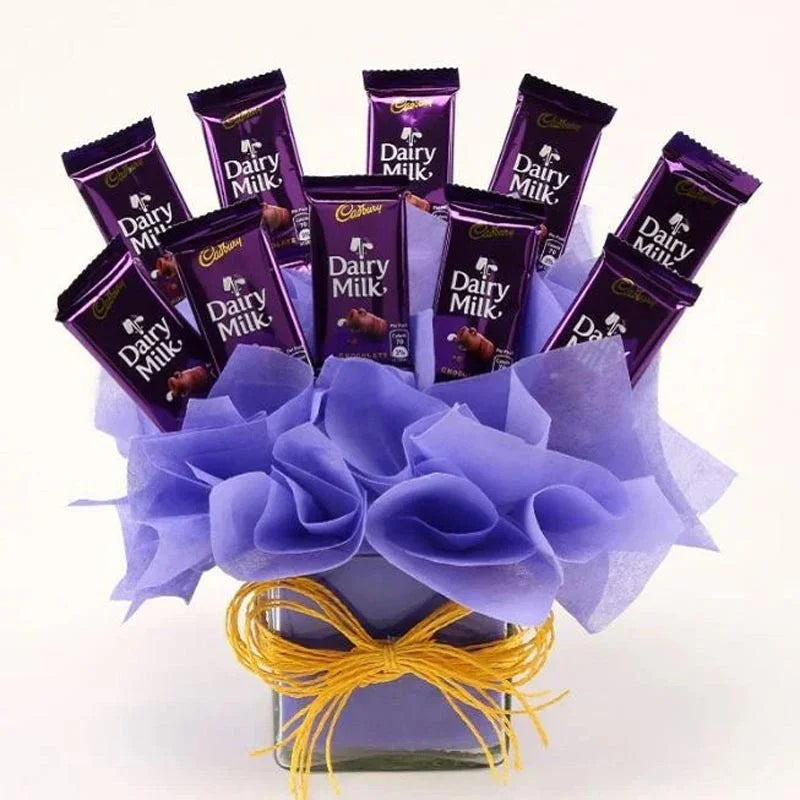Bouquet of Cadbury Dairy Milk chocolate bars arranged in a decorative box with purple flowers and a yellow ribbon.