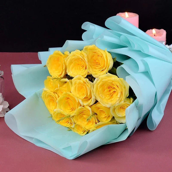 Bouquet of yellow roses wrapped in light blue paper on a dark background