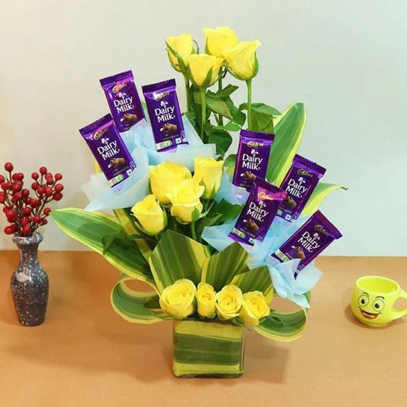 Bouquet of yellow roses with Dairy Milk chocolate bars on a table.