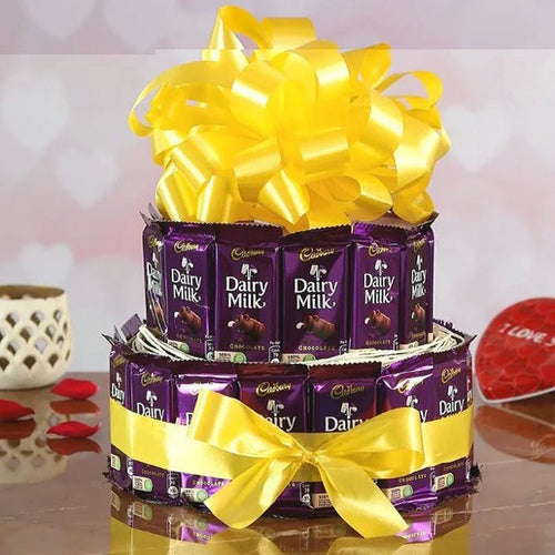 Two-tiered chocolate gift set with Cadbury Dairy Milk bars and yellow ribbons on a reflective surface.