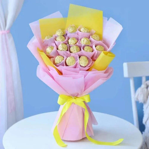 Bouquet of Ferrero Rocher chocolates wrapped in pink and yellow paper on a white surface with a blue background.