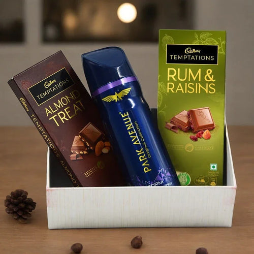 Gift set with Cadbury Temptations, Park Avenue deodorant, and a box of chocolates on a wooden surface.
