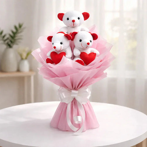 Bouquet of teddy bears with red hearts wrapped in pink paper on a white table.